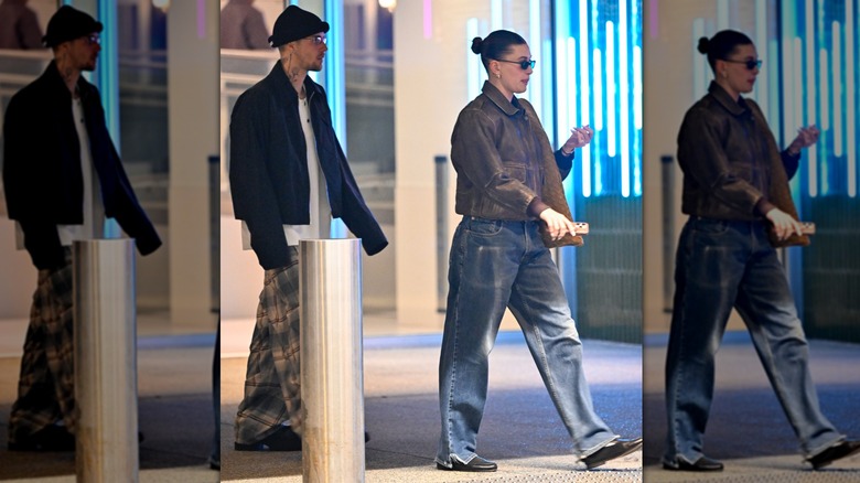 Hailey Bieber wearing blue jeans and a brown bomber jacket and Justin Bieber wearing oversized patterned trousers