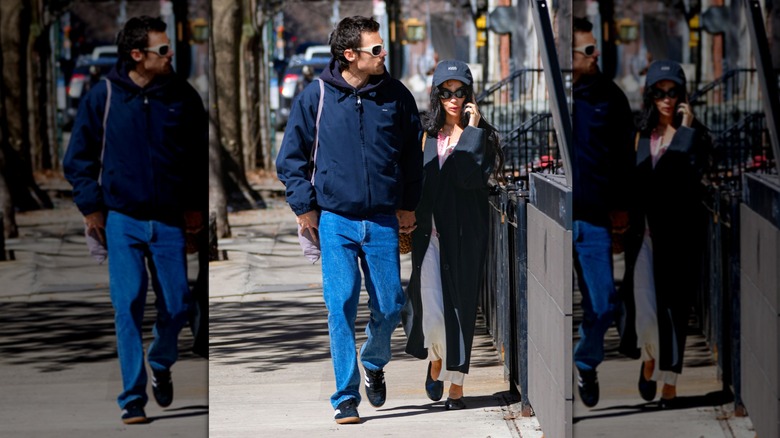 Zoë Kravitz wearing black sunglasses and a white skirt and Harry Styles walking wearing blue jeans and white sunglasses