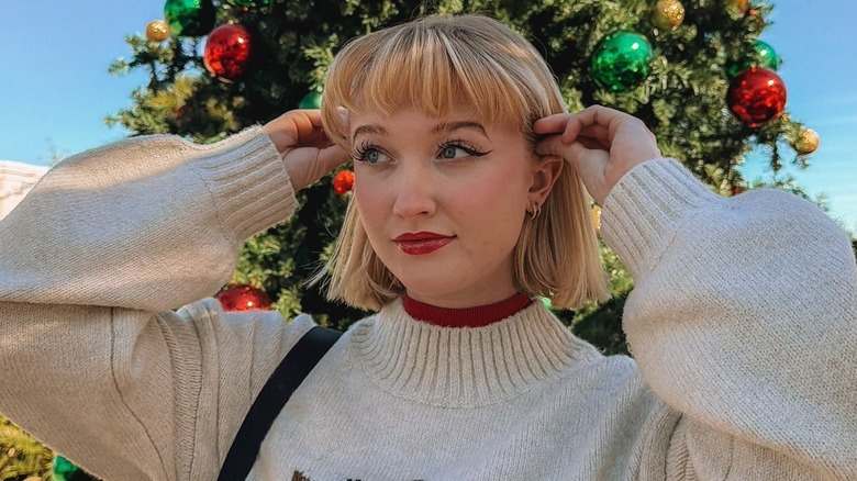 A woman with a bob posing in front of a Christmas tree