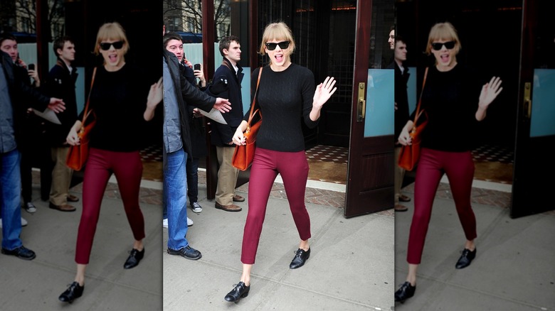 Taylor Swift wearing maroon trousers and black Oxford flats