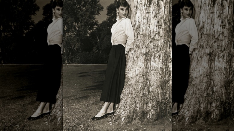 Audrey Hepburn wearing a black skirt and a white shirt with black pumps