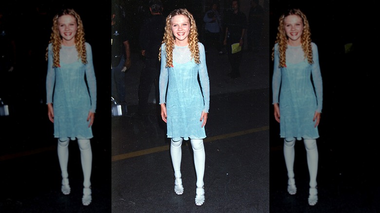 Kirsten Dunst smiles wearing a blue glitter dress and jelly flats