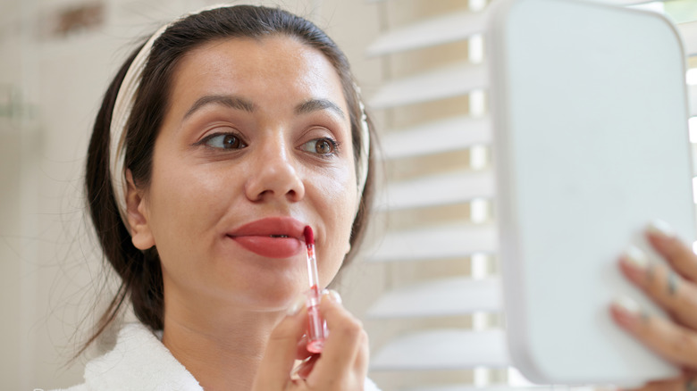 Close-up of a girl applying liquid lipstick or lip balm, lip care cosmetics