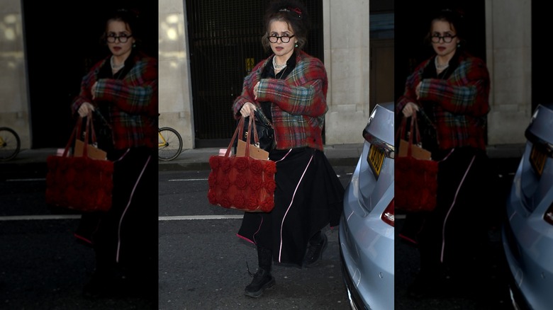 Helena Bonham Carter walks wearing a black skirt and a red tartan jacket