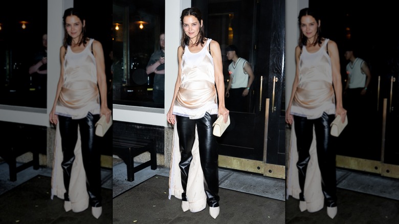 Katie Holmes smiles wearing a beige slip dress over leather trousers