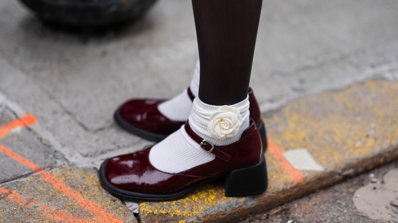 ﻿﻿Close-up of maroon Mary Janes with a chunky heel wore with black tights and white socks