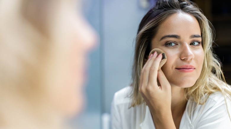 A woman applying powder to her face