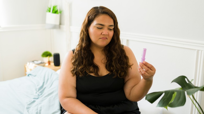 Image of woman looking at her tampon with upset expression