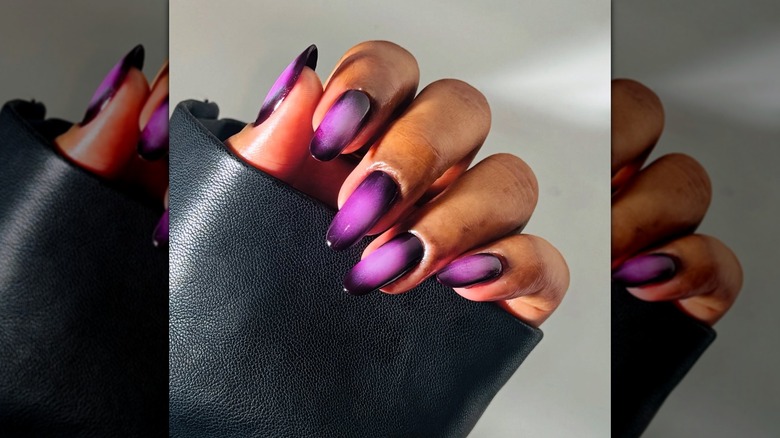 A woman with purple aura nails wearing a leather coat on Instagram
