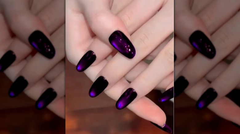 A close up of purple cat eye nails on Instagram