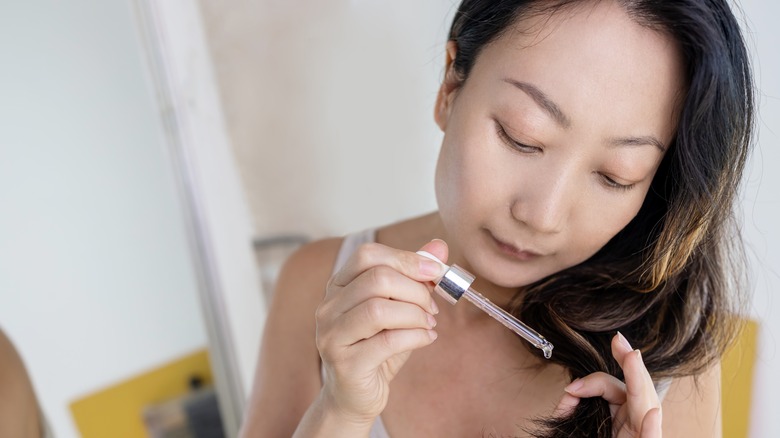 Woman putting oil in hair