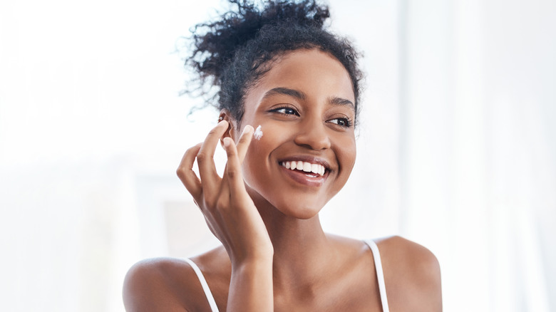woman applying cream on face