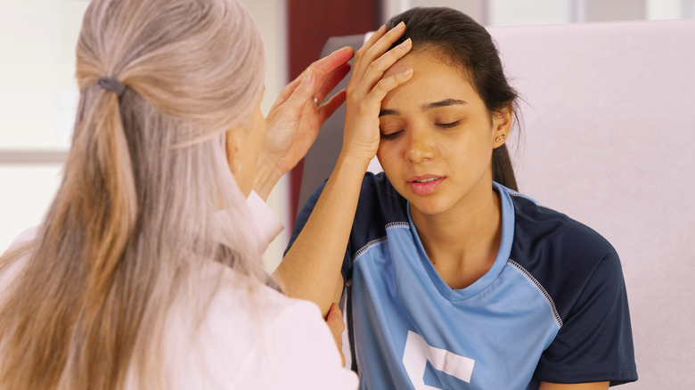 Young female athlete being treated by a doctor for a head injury.
