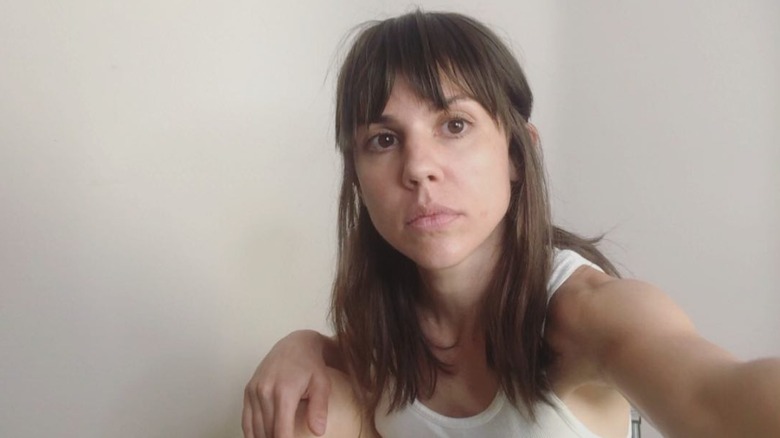 Kate Mansi wearing a white tank top and minimal makeup with brunette haircut and bangs in a 2020 selfie.