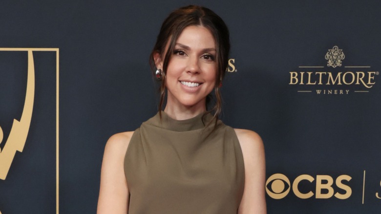 Kate Mansi posing in a khaki green, high neck dress on the red carpet