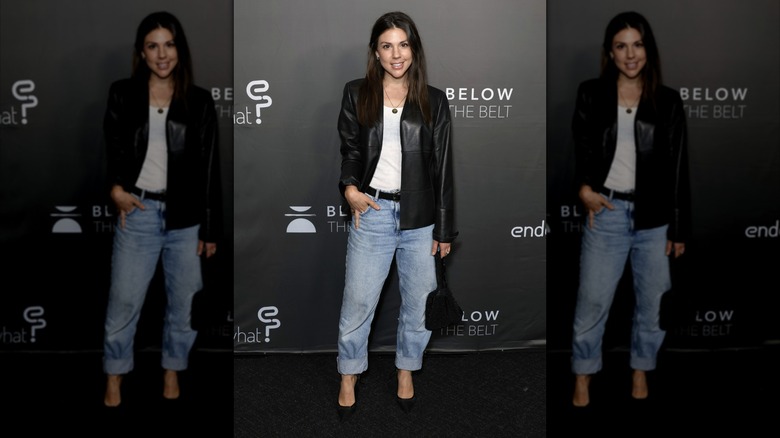 Kate Mansi wearing a black leather look jacket with a white top and jeans at a "Below The Belt" screening in 2022