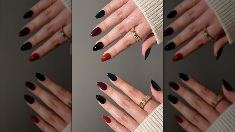 Hands featuring a Skittles manicure with each nail painted a different dark color
