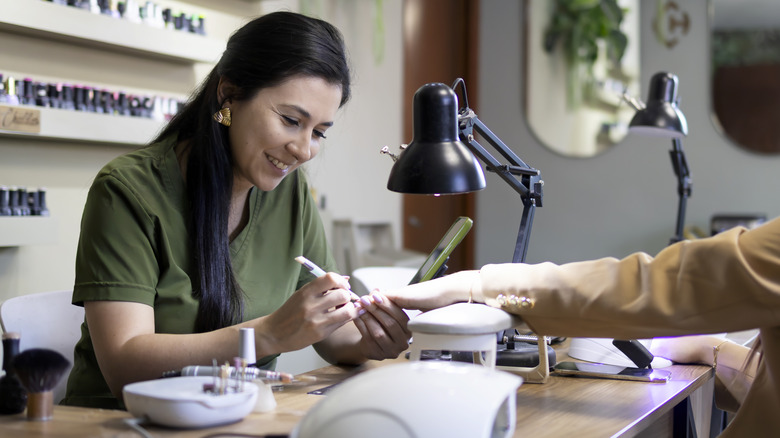 A woman doing a manicure on another woman's hand in a nail salon