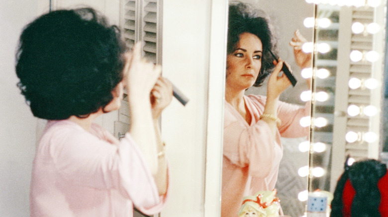 Elizabeth Taylor teasing her hair in the mirror