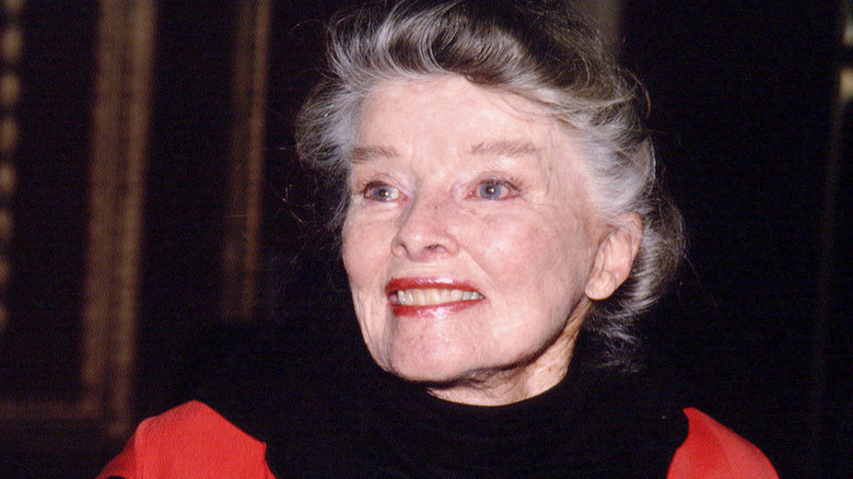 Katharine Hepburn similing at an event in New York City wearing black and red