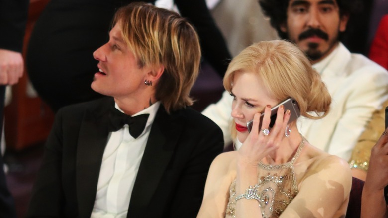 Nicole Kidman on her phone sitting next to Keith Urban