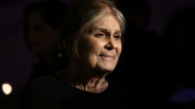 Gloria Steinem slightly smiling in front of a black background