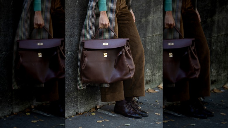 A woman holding a brown purse and wearing brown derby shoes