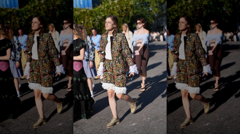 A woman wearing a floral ruffled set and cream derby shoes