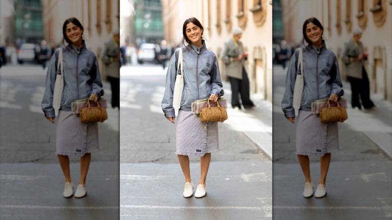 A woman on the street wearing a shirt, windbreaker, and cream derby shoes