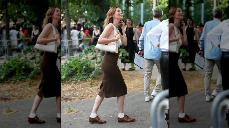 A woman walking on the street in a brown street and brown derby shoes