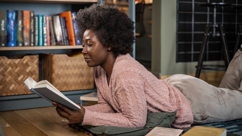 A woman laying on the floor and reading a book