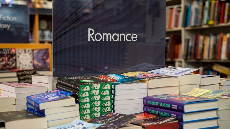 A collection of books in a bookstore under a romance sign