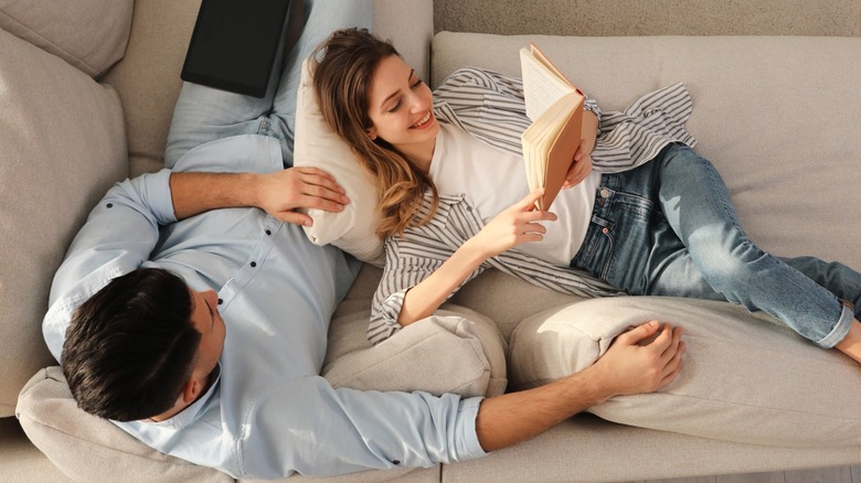 Birds eye view photo of a couple on a sofa with the woman reading a book