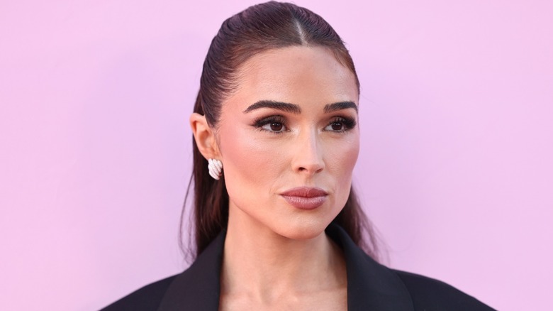 Olivia Culpo posing in front of a pink background