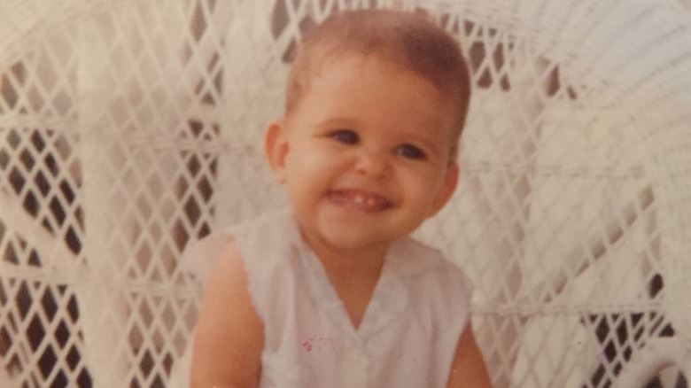 Jill Wagner smiling as a baby in a white dress
