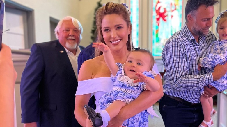 Jill Wagner in a white dress holding her youngest daughter in 2022