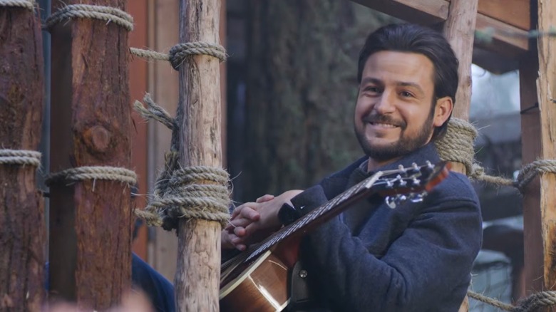 Tyler Hynes playing the guitar outside on a wooden porch in "It Was Always You"