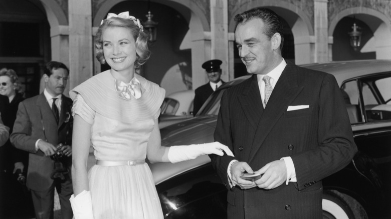 Prince Rainier and Grace Kelly standing next to a car