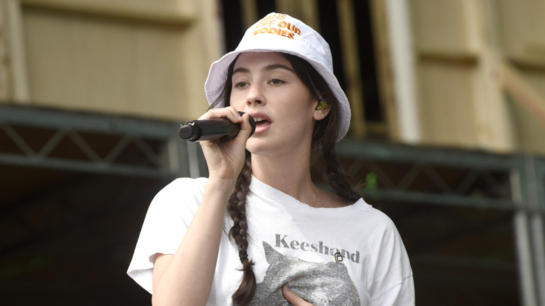 Gracie Abrams singing while wearing a bucket hat and white t-shirt