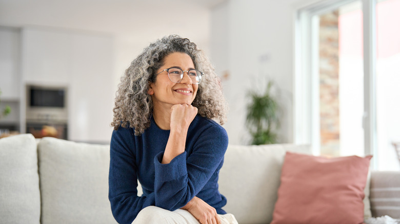 women with curly gray hair smiling in a blue crewneck jumper