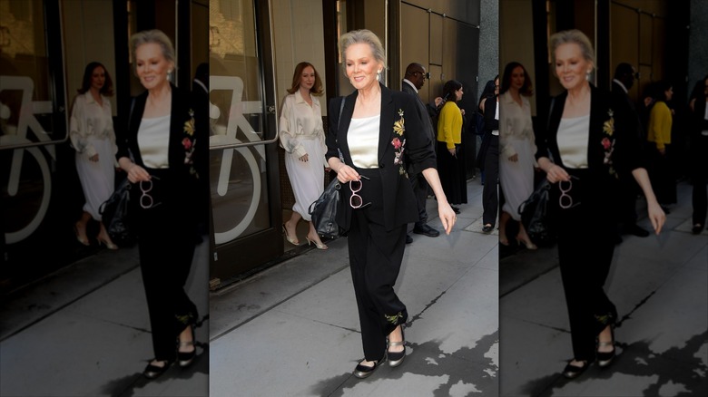 Jean Smart walking on the street wearing a black pantsuit