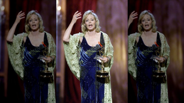 Jean Smart waves while speaking into a microphone wearing a blue velvet dress