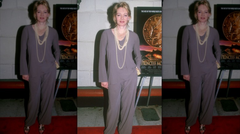 Jean Smart smiles wearing a gray panstuit and pearl necklaces