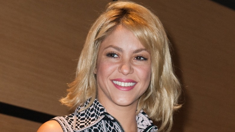 Shakira smiling with a messy bob haircut during a visit to France in 2012