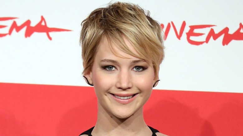 Jennifer Lawrence smiling on the red carpet with short, blonde hair