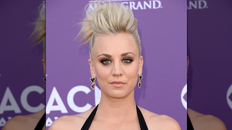 Kaley Cuoco posing on the red carpet with a tall, blonde pompadour haircut
