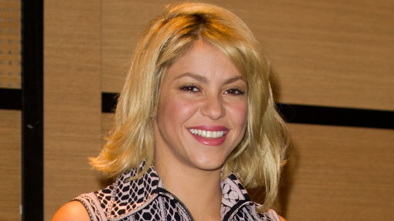 Shakira smiling with a messy, blonde bob
