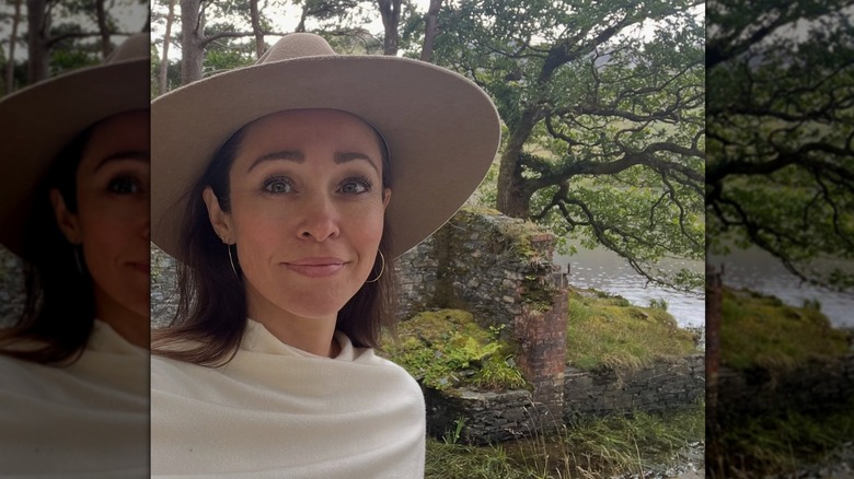Autumn Reeser posing in a nature setting in front of an old brick structure