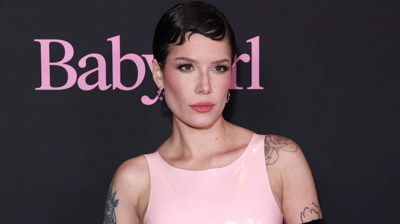 Halsey posing at a movie premiere with short, black hair and a pink, latex dress