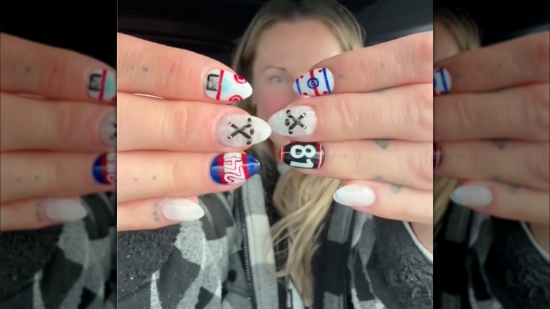 A person showing off their "Heated Rivalry" nails on their tattooed hands